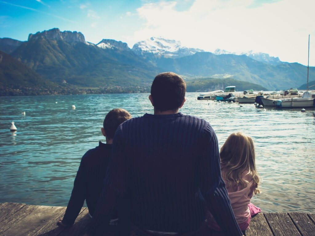 man and woman sitting on brown wooden dock during daytime