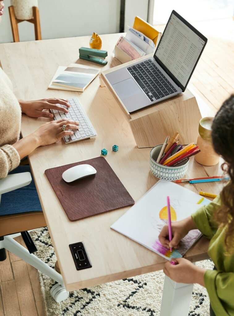 a woman sitting at a table with a child using a laptop