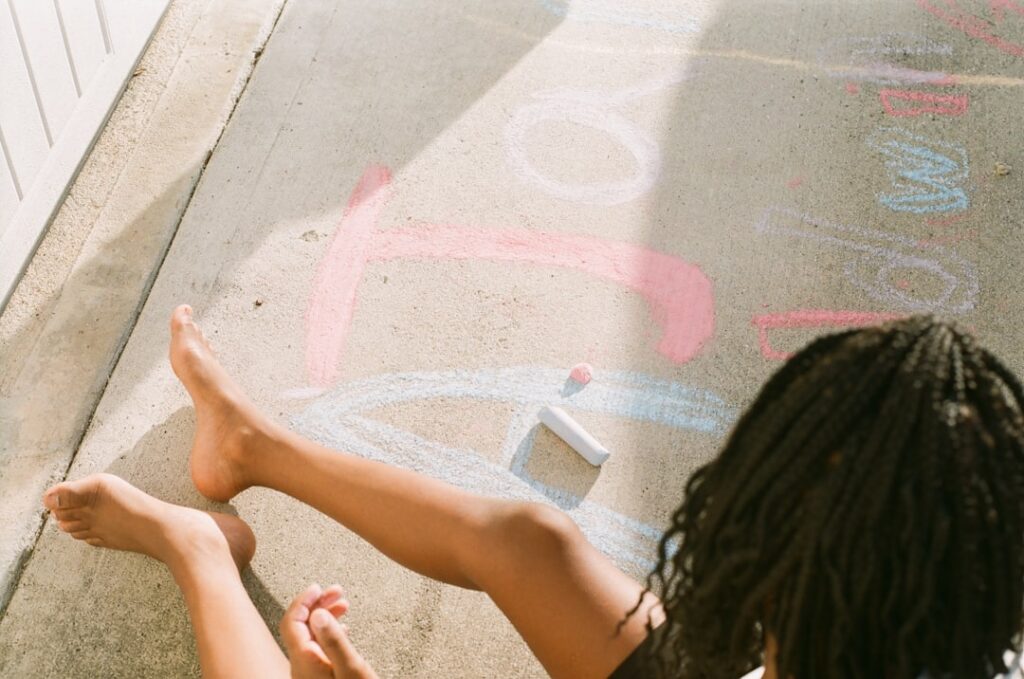 A person sitting on the sidewalk with their feet up