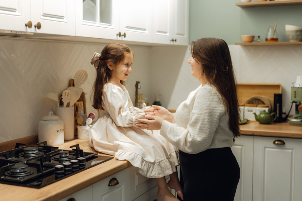 Two girls in a kitchen talking to each other
