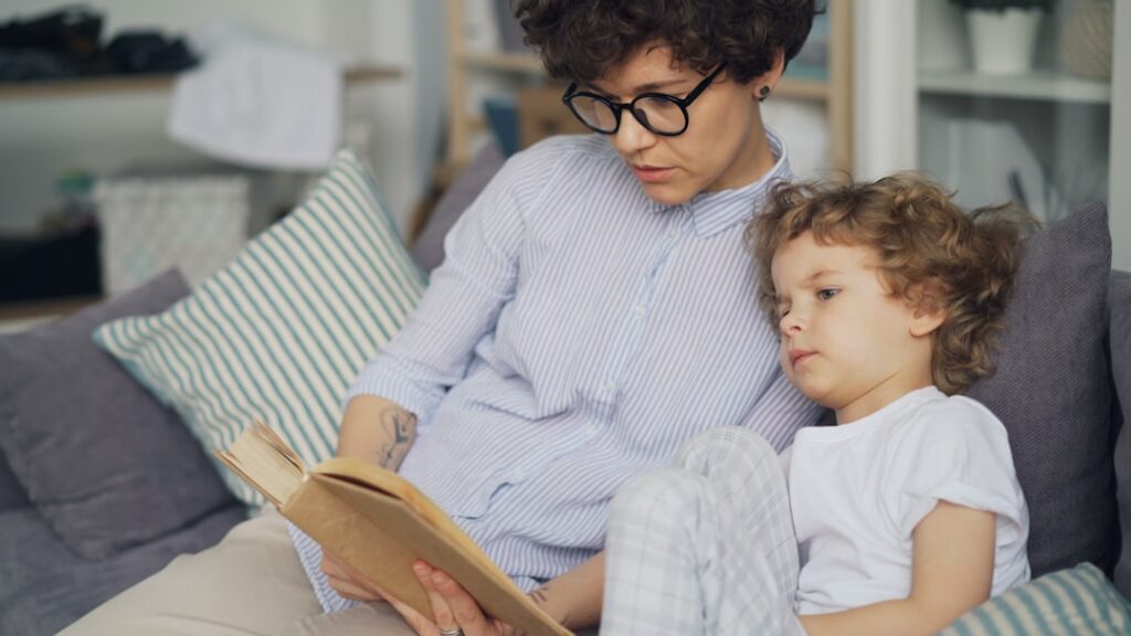 a woman sitting on a couch reading a book to a child