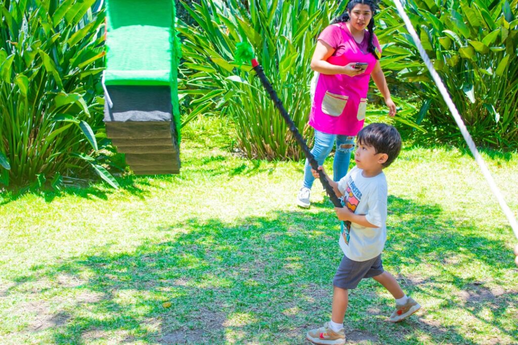a young boy holding a baseball bat next to a woman